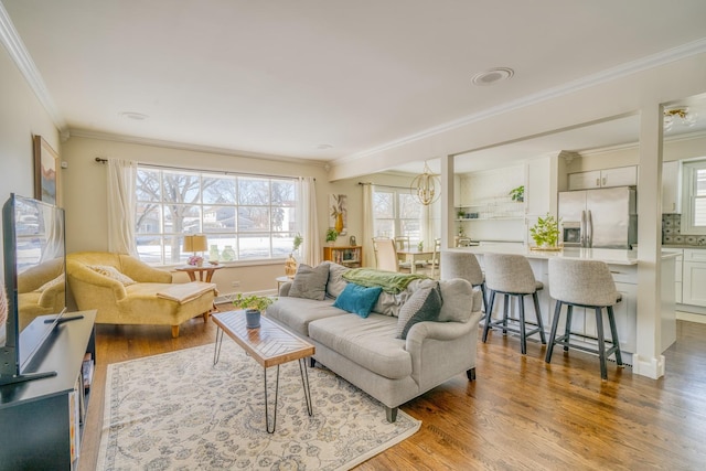 living room featuring light hardwood / wood-style floors, a chandelier, and crown molding