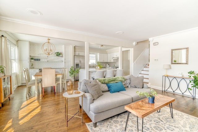 living room featuring light hardwood / wood-style floors, crown molding, and a healthy amount of sunlight