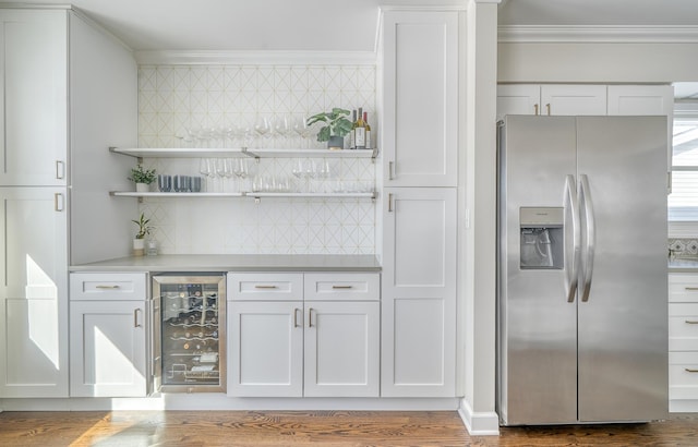 bar featuring tasteful backsplash, white cabinets, crown molding, stainless steel fridge, and beverage cooler