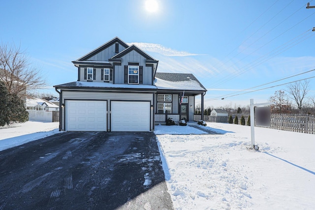 view of front of property featuring aphalt driveway, an attached garage, board and batten siding, and fence