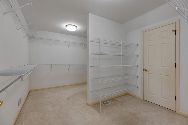 walk in closet featuring light colored carpet