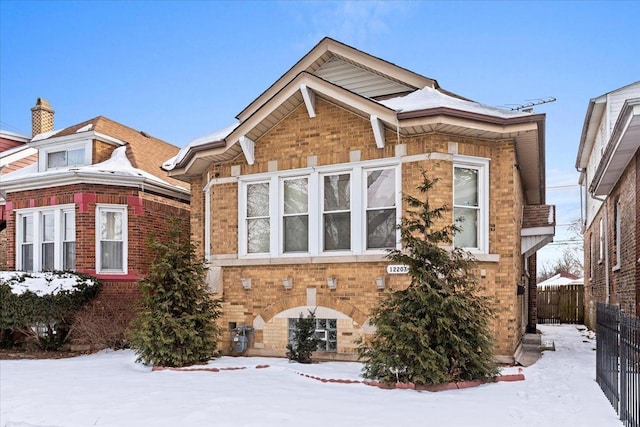 view of snowy exterior with fence and brick siding