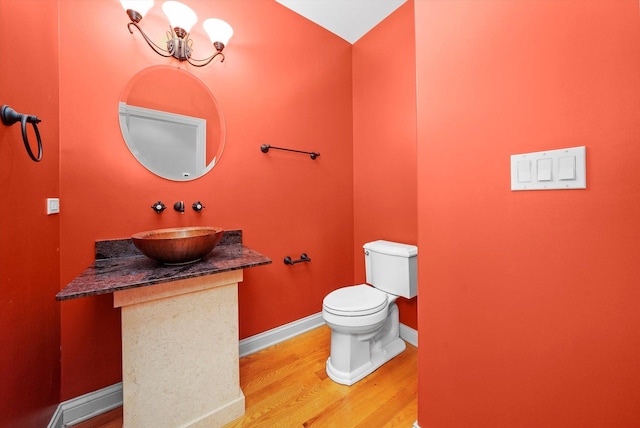 bathroom featuring wood-type flooring, vanity, a chandelier, and toilet