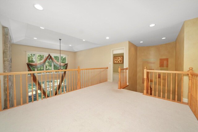 hallway with carpet and a raised ceiling