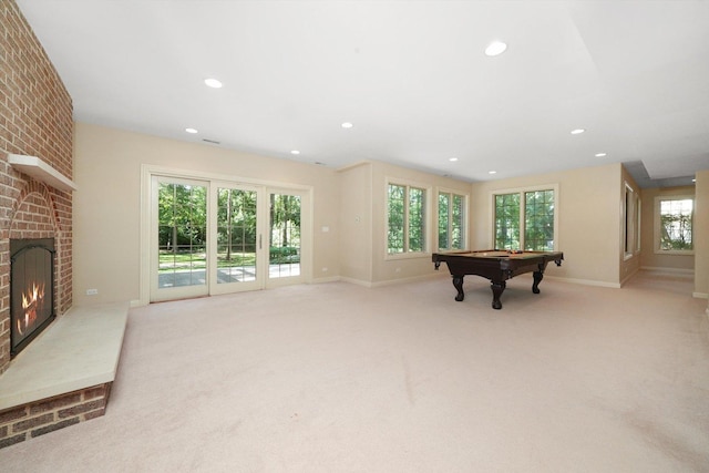 recreation room featuring a brick fireplace, light carpet, billiards, and plenty of natural light