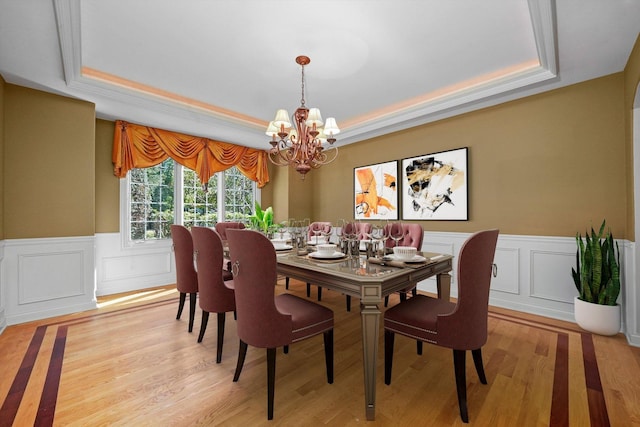 dining room featuring light hardwood / wood-style flooring, a notable chandelier, and a raised ceiling