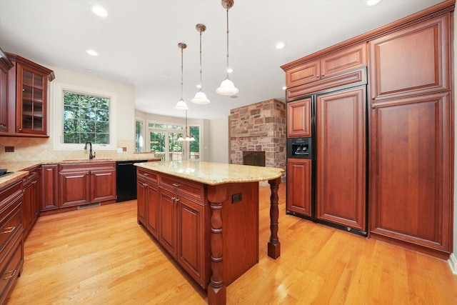 kitchen featuring a center island, decorative light fixtures, black dishwasher, sink, and paneled refrigerator