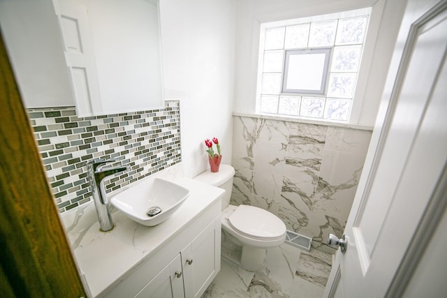 bathroom featuring visible vents, decorative backsplash, toilet, marble finish floor, and vanity