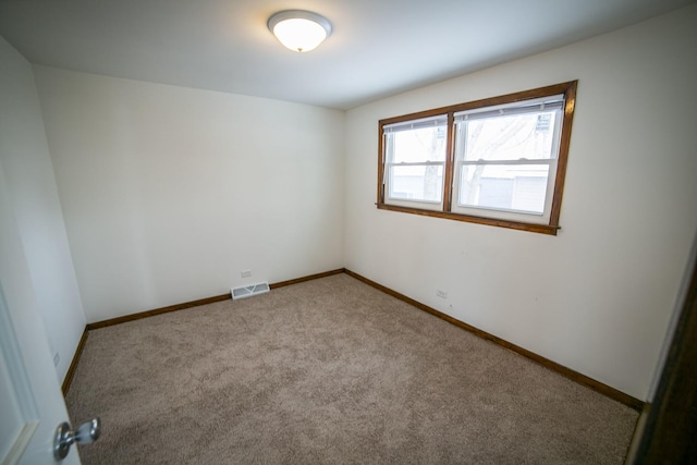 carpeted spare room with visible vents and baseboards