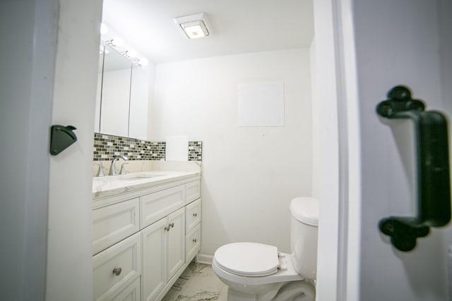 half bath featuring marble finish floor, tasteful backsplash, toilet, vanity, and baseboards