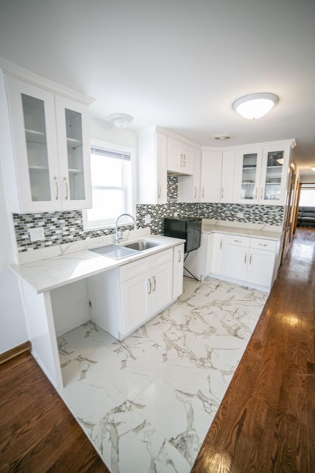 kitchen featuring light stone countertops, a sink, glass insert cabinets, and white cabinets