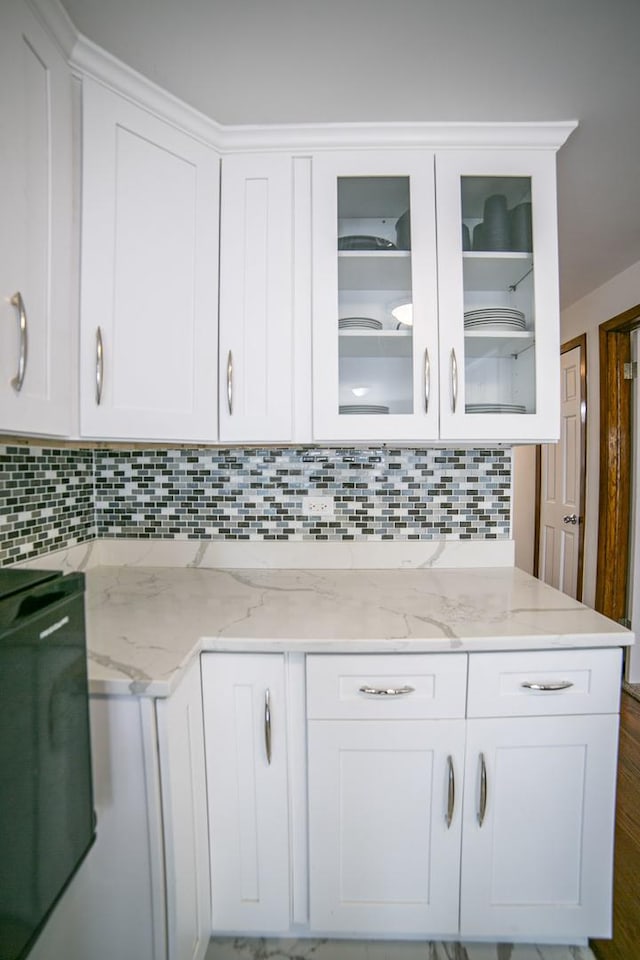 kitchen with decorative backsplash, glass insert cabinets, white cabinets, and light stone counters