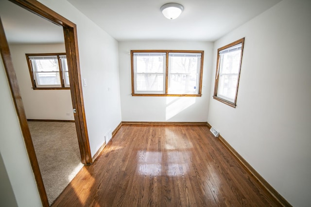 unfurnished room featuring visible vents, baseboards, and wood finished floors