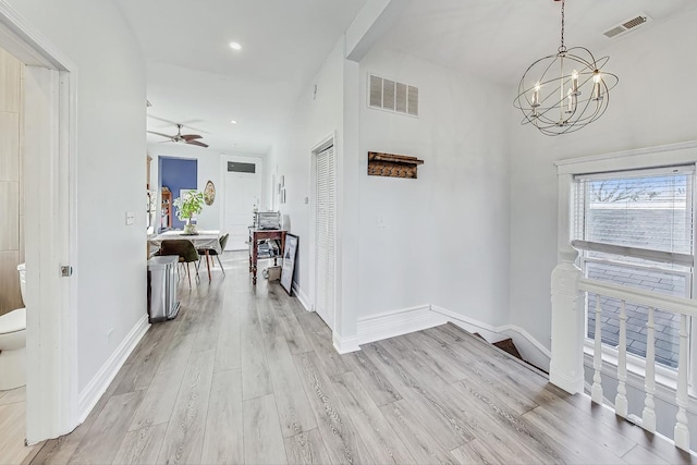 corridor with an inviting chandelier and light hardwood / wood-style flooring