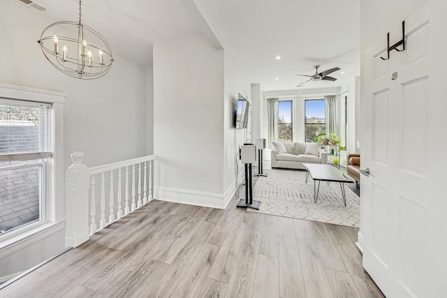 interior space featuring ceiling fan with notable chandelier and light hardwood / wood-style floors