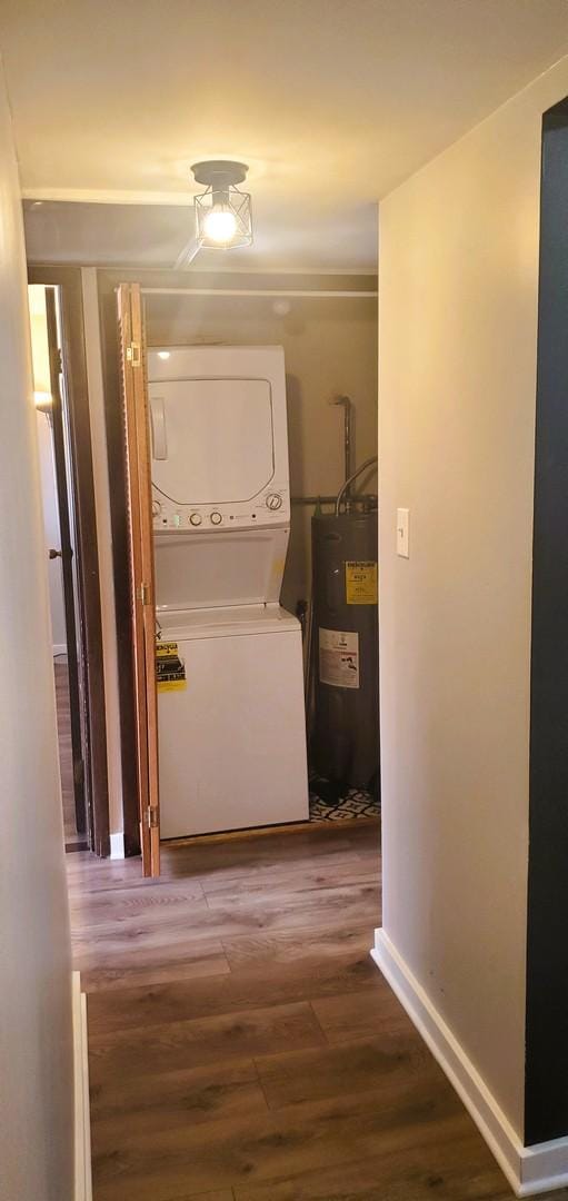 washroom with hardwood / wood-style floors, water heater, and stacked washer and dryer