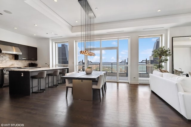 dining room featuring recessed lighting, dark wood-style flooring, and a tray ceiling