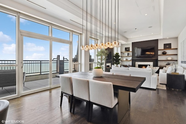 dining space featuring dark wood finished floors, a fireplace, a tray ceiling, and recessed lighting