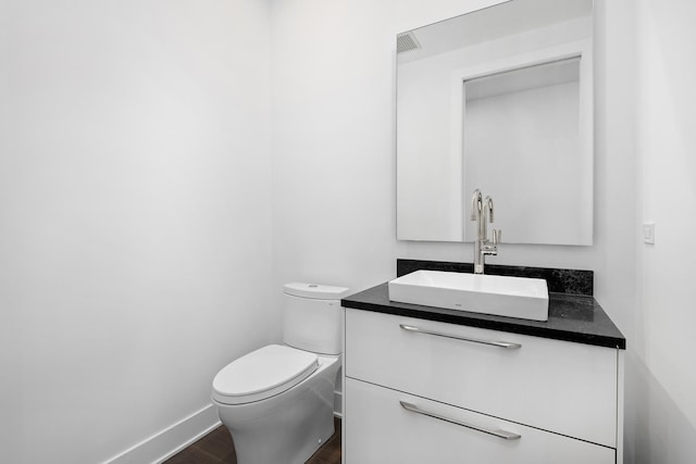 bathroom featuring wood-type flooring, vanity, and toilet