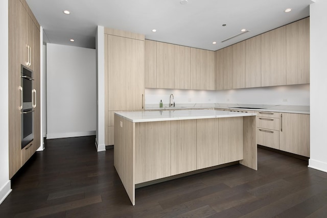 kitchen with dark hardwood / wood-style floors, a kitchen island with sink, light brown cabinets, and white electric cooktop