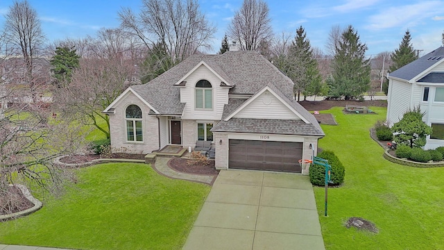 traditional-style house with brick siding, a shingled roof, concrete driveway, and a front yard