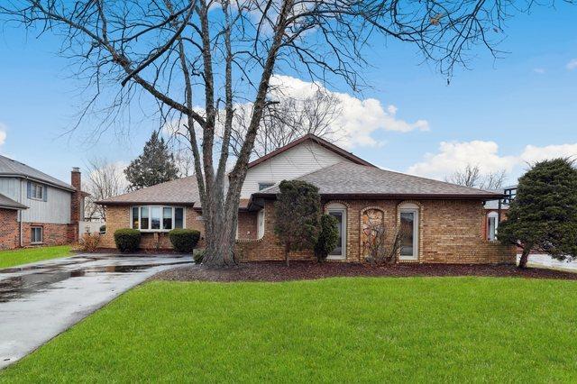 ranch-style house with driveway, brick siding, and a front yard