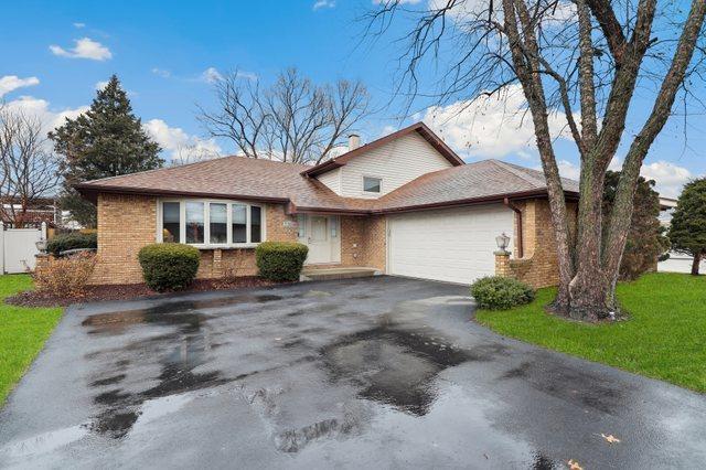 tri-level home featuring a garage, aphalt driveway, a front yard, and brick siding