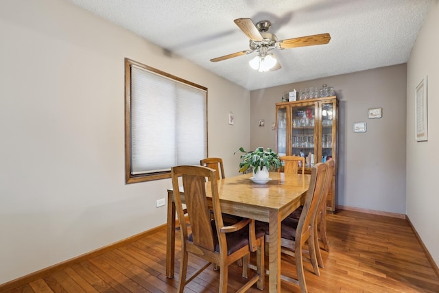 dining space with a textured ceiling, ceiling fan, light wood-style flooring, and baseboards