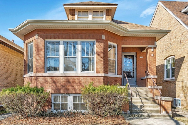 view of front of house with brick siding and roof with shingles