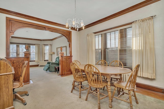 dining area featuring crown molding, baseboards, light carpet, arched walkways, and a notable chandelier