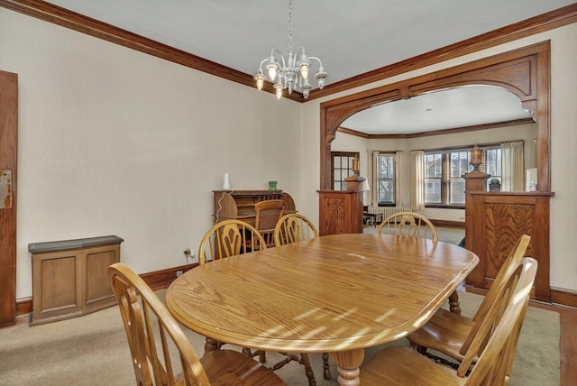 dining area with arched walkways, light colored carpet, a chandelier, and ornamental molding