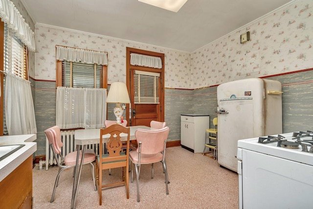 dining space featuring ornamental molding, wainscoting, and wallpapered walls