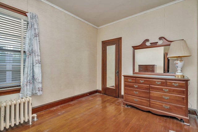 bedroom featuring baseboards, wood finished floors, ornamental molding, and radiator heating unit