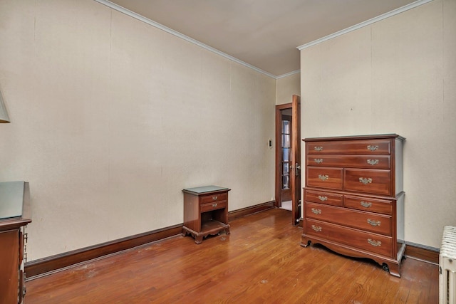 bedroom featuring light wood finished floors, radiator heating unit, crown molding, and baseboards