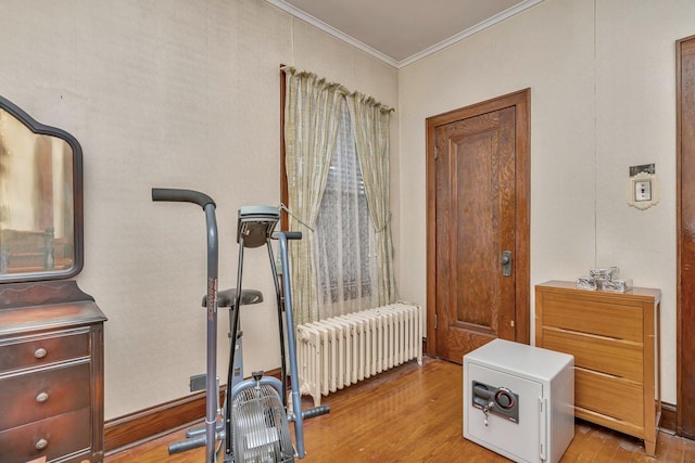 exercise area with light wood-type flooring, radiator, and ornamental molding