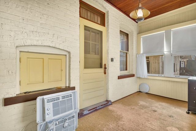 view of exterior entry with an AC wall unit and radiator heating unit