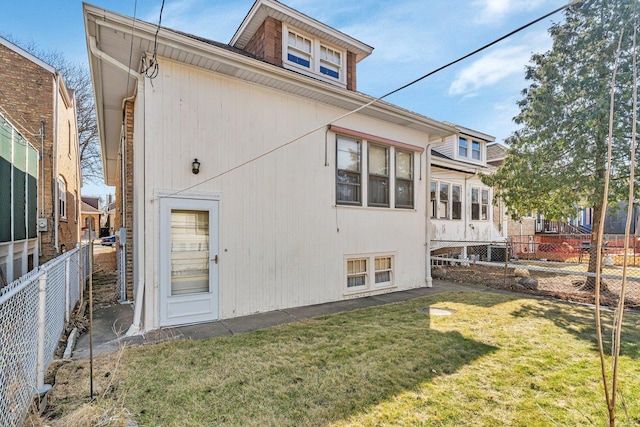 rear view of house with a lawn and fence