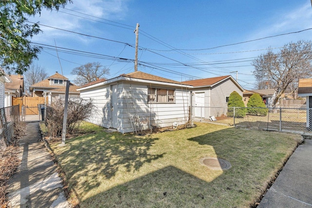 view of side of home featuring a lawn, an outdoor structure, and fence