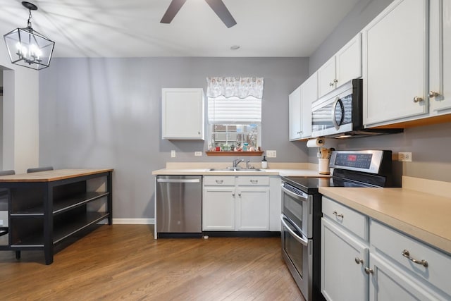 kitchen featuring white cabinetry, appliances with stainless steel finishes, sink, and hanging light fixtures