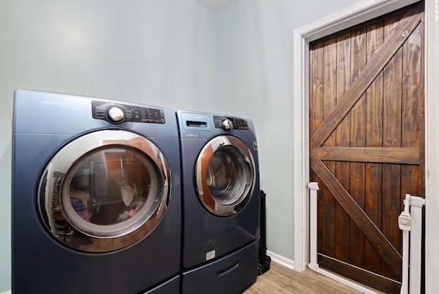 clothes washing area featuring washer and dryer, a barn door, and light hardwood / wood-style flooring