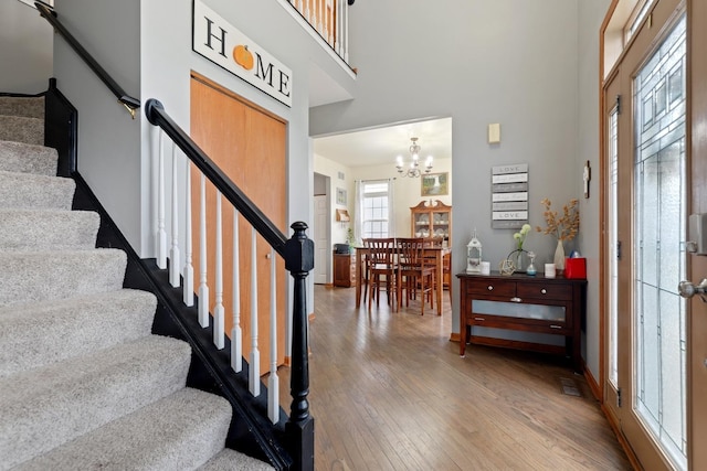 foyer entrance with a notable chandelier, hardwood / wood-style flooring, and a high ceiling