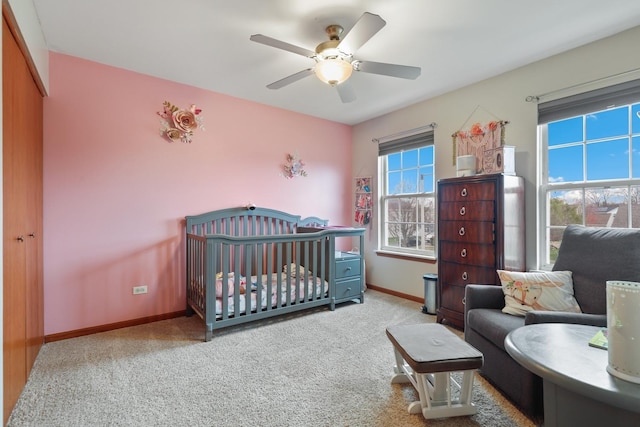 carpeted bedroom with ceiling fan and a nursery area