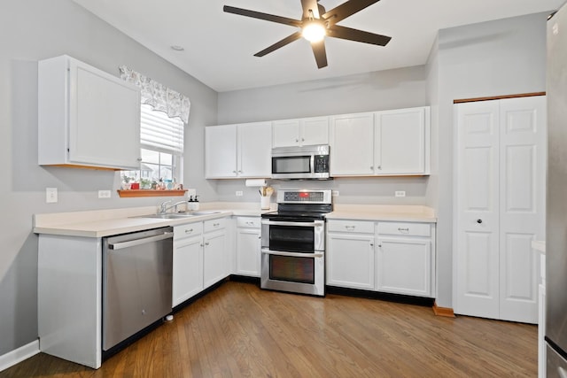 kitchen with appliances with stainless steel finishes, sink, light hardwood / wood-style flooring, ceiling fan, and white cabinets