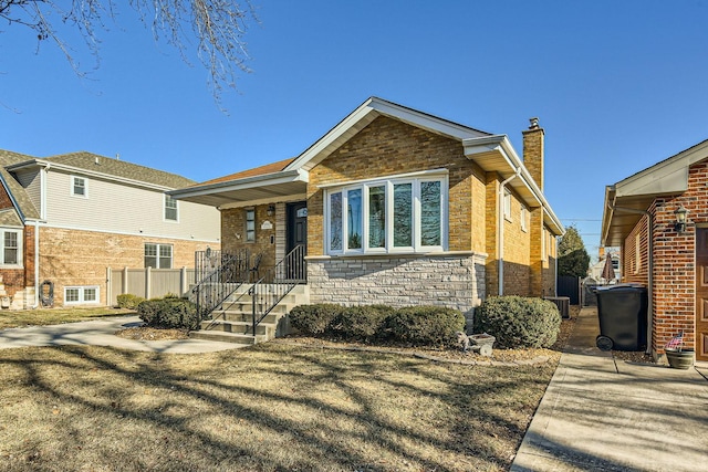 view of front of house with stone siding, a chimney, and a front lawn