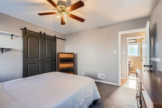 carpeted bedroom featuring a barn door, ceiling fan, baseboards, and visible vents