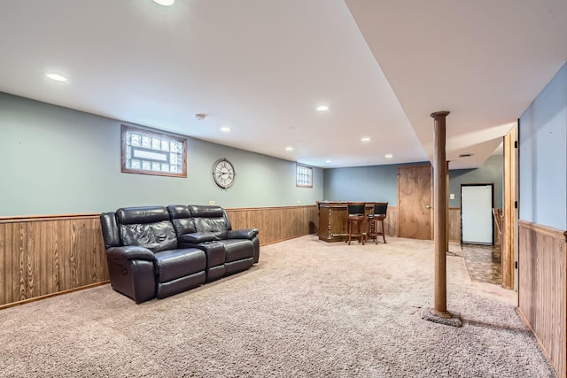 living area featuring wood walls, light colored carpet, a wainscoted wall, and a wealth of natural light