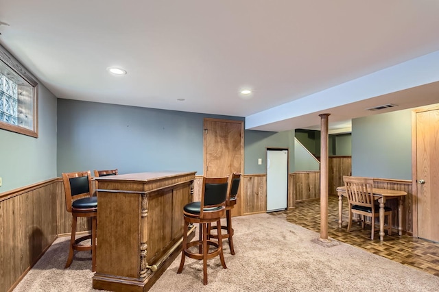 bar with a wainscoted wall, a dry bar, and wood walls