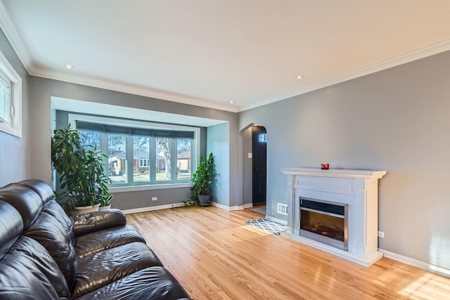 unfurnished living room with a glass covered fireplace, light wood-type flooring, arched walkways, and baseboards