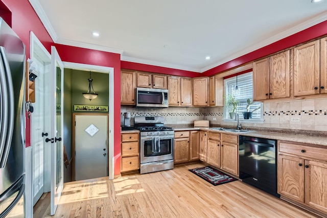 kitchen featuring light wood finished floors, stainless steel appliances, brown cabinets, and a sink