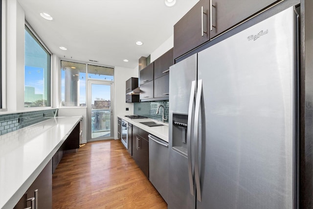 kitchen featuring light wood-type flooring, light countertops, appliances with stainless steel finishes, modern cabinets, and a sink